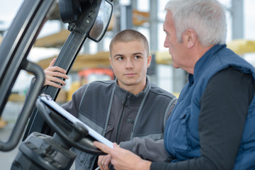 Young man talking to driver of forklift