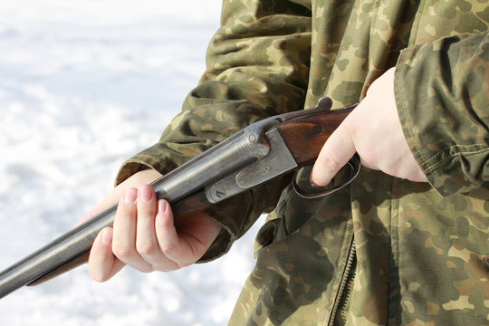 Close-up of a hunter holding his old 16 caliber side-by-side double-barreled shotgun in winter forest