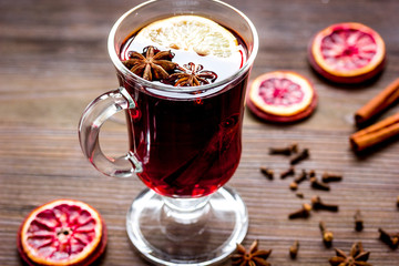 mulled wine with spices in cup on wooden background