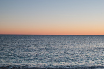 Open sea at sunset with colorful gradient sky background, horizon line splitting the photo in half