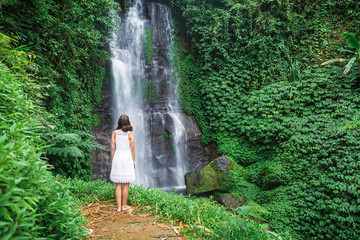 Beautiful asian girl in white dress. Waterfall in tropical jungle on Bali