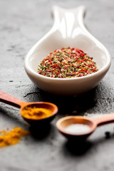 spices in wooden spoon on dark background