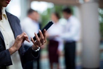 Mid section of female business executive using mobile phone