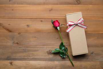 Red rose and vintage gift box on vintage wood background