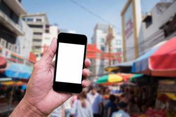 Man's hand holding and using mobile,cell phone,smart phone with isolated screen with blur image of people for background.