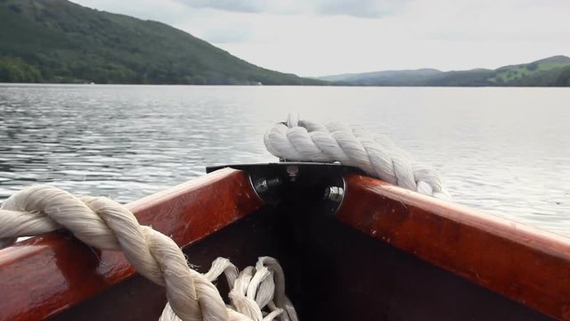 The bow of a rowing boat point of view (POV), rocking a little as the boat is rowed across Coniston Water in the English Lake District.