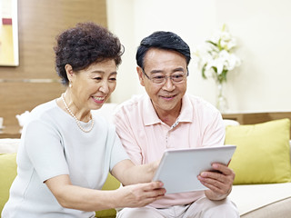 happy senior asian couple using tablet computer together
