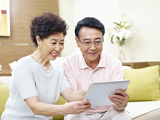 Obraz premium happy senior asian couple using tablet computer together