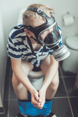 Young boy on toilet wearing gas mask