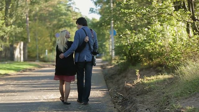 Young couple embracing and walking in park