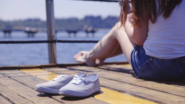 Canvas shoes and woman relaxed on wooden pier 4K
