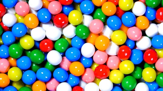 A rotating bowl of sweet candy gumballs in various bright colors.