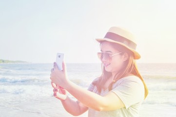 Yong woman traveler relaxing and  taking vacation selfie photograph at the beach. Technical Writing light synthesizer