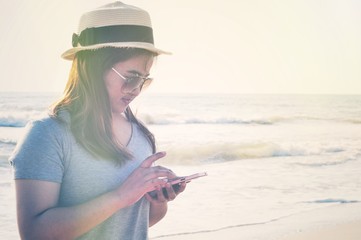 Yong woman traveler relaxing and use mobile phone on a perfect beach