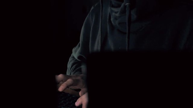 Hacker in VR glasses cracking code using computers in dark room