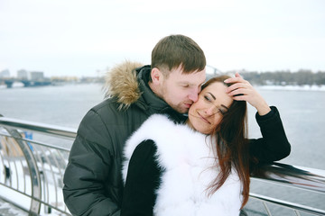 Winter love story. Young couple engagement outdoors near the riv