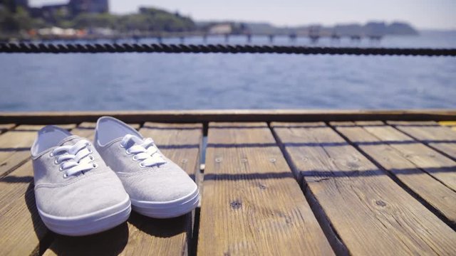 Cute textile shoes sliding over on wooden pier 4K