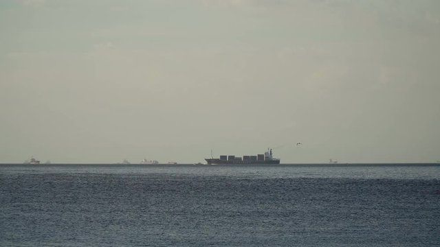 Cargo ship with containers floating on the sea. Cargo ships in the Bay of Manila. Large container ship in the sea, blue sky and clouds. 4K video. Philippines, Manila.