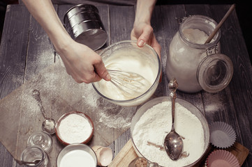 Graceful female hands prepare dough for cupcakes. Home-made pastries. Soft vintage toning
