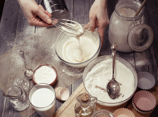 Graceful female hands prepare dough for cupcakes. Home-made pastries. Soft vintage toning