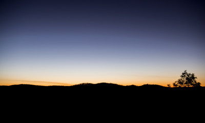 Sunset over the horizon set against the silhouette of mountains