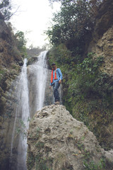 Fototapeta premium Traveler standing on a rock near waterfall