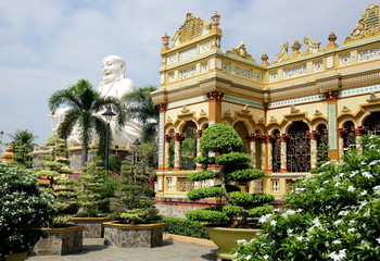 Smiling Buddha in one of the Buddhist pagodas in Vietnam.  A huge white statue of a sitting and beaming smile of the Buddha at the Vinh Tranh Pagoda in My Tho