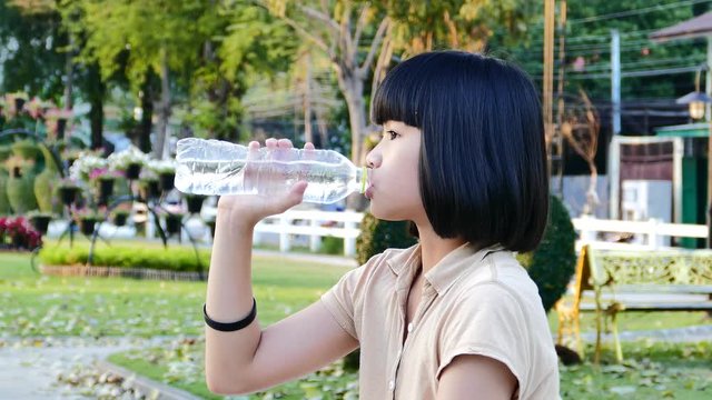 Asia girl drinking water from bottle at park.