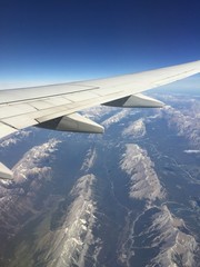 Aerial view of rocky mountains and airplane wing