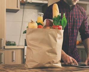 Full paper bag of healthy food on wooden table closeup