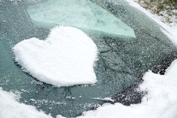 snow in heart shape on windshield of the car