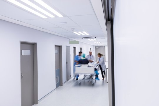 Doctors and nurse pushing emergency stretcher bed in corridor