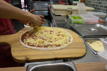How to make pizza, sprinkle pizza with cheese