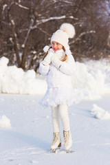 cute little girl on a skating rink in winter snowy day
