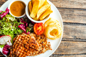 Grilled pork steak with vegetables salad and french fries