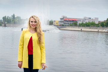 Blonde in a yellow dress against the backdrop fountain
