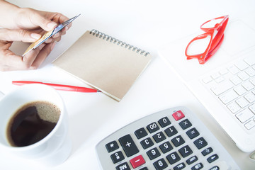 Woman hand holding credit card and using calculator with laptop,