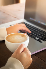 Woman working with laptop and hot coffee