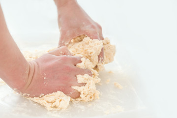 Hands knead dough