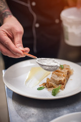 Male cook decorating strudel on plate