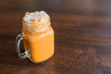 thai ice tea with milk in Glass handle on wooden table.