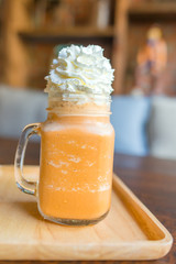 thai ice tea with milk in Glass handle on wooden table.