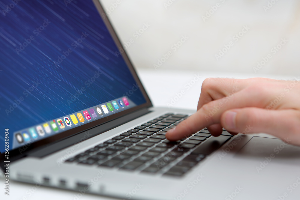 Wall mural hand typing on a keyboard of laptop with operating system screen on background