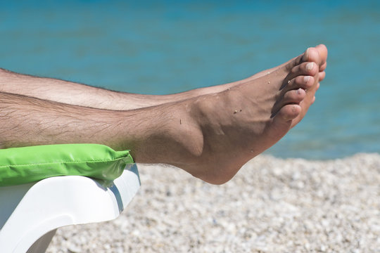 Men's feet on a lounger near the sea