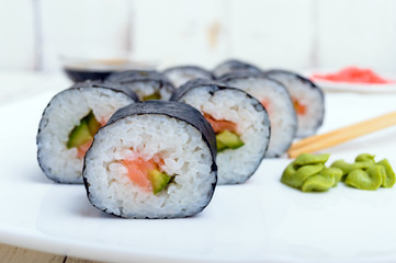 Traditional eastern dish with salmon sushi rolls on a white plate. Close-up.