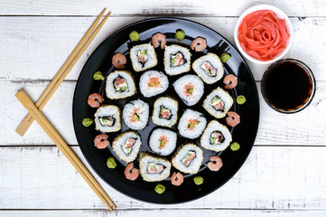 Traditional eastern dish with salmon sushi rolls on a black plate. The top view