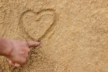 Man drawing a heart in the sand on beach, Valentine's concept.