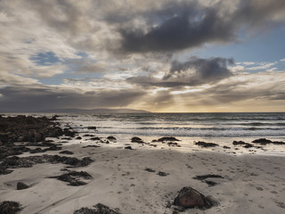 Empty beach under cloudy sky.
