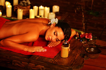 Massage of woman in spa salon. Girl on candles background in massage spa salon. Luxary interior in oriental therapy salon. Female have relax after sport.