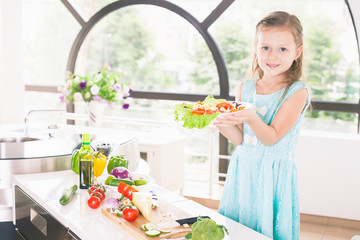 Cute little girl making salad. Child cooking. Healthy food
